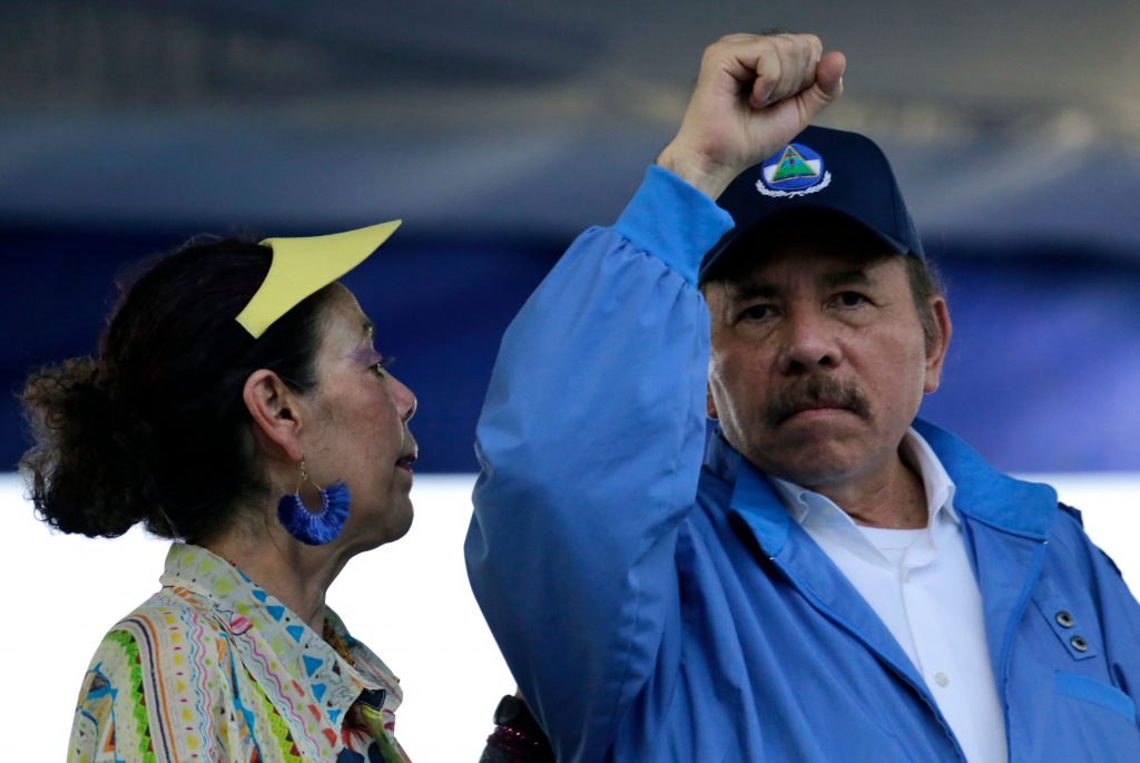 Nicaraguan President Daniel Ortega raises his fist next to his wife, Vice-President Rosario Murillo during the commemoration of the 51st anniversary of the Pancasan guerrilla campaign in Managua, on August 29, 2018.