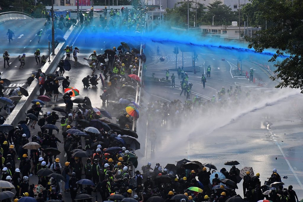 TOPSHOT - Pro-democracy protesters react as police fire water cannons outside the government headquarters in Hong Kong on September 15, 2019. - Hong Kong riot police fired tear gas and water cannons on September 15 at hardcore pro-democracy protesters hurling rocks and petrol bombs, in a return to the political chaos plaguing the city. (Photo by NICOLAS ASFOURI / AFP) (Photo by NICOLAS ASFOURI/AFP via Getty Images)