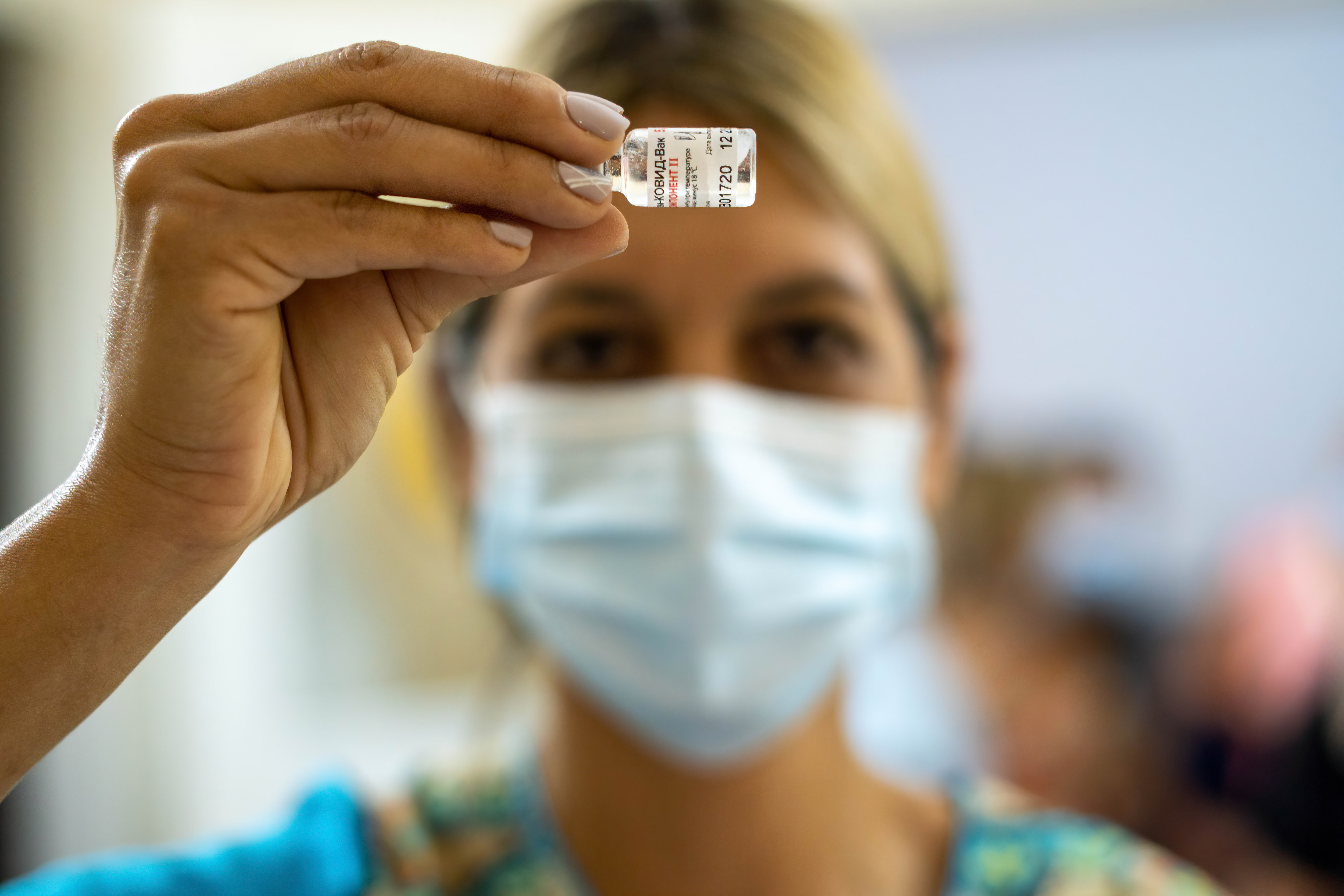 Nurse Monica Arrieta looks at a vial of Sputnik V vaccine to